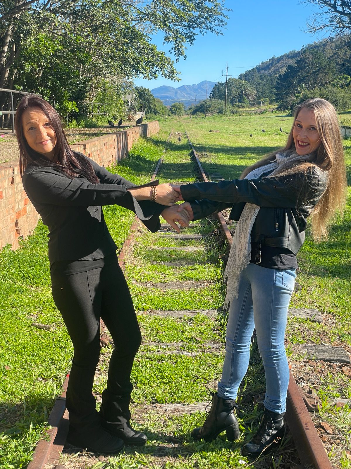 Tracey and Lindie holding hands on a railway track